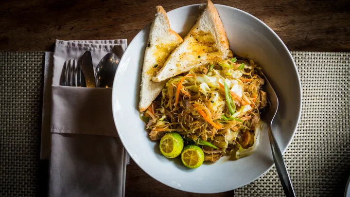 A bowl of pancit canton noodles with vegetables and calamansi