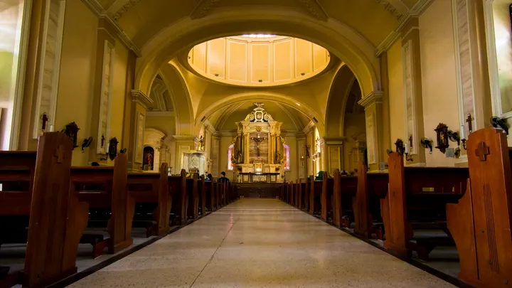 Interior of San Pablo Cathedral, warm golden light illuminating wooden pews